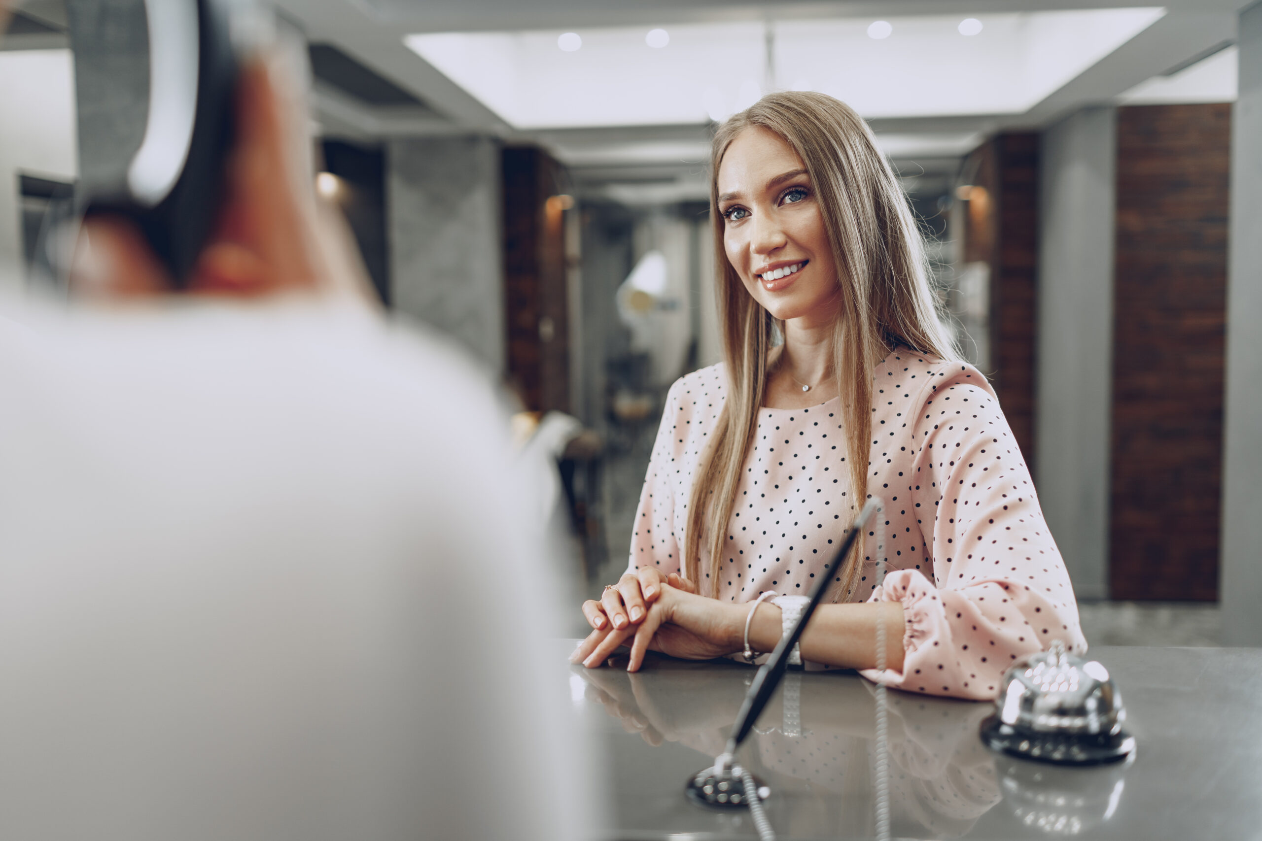 Blonde woman hotel guest checking-in at front desk in hotel